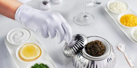 Hand met witte handschoen en schaaltje kaviaar
