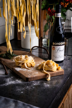 Verse pasta op houten plank met fles wijn