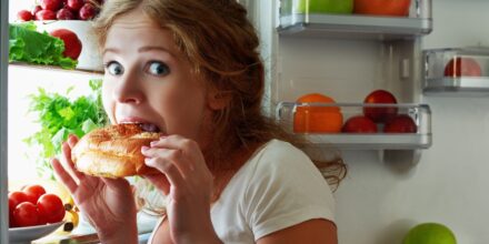 vrouw eet uit de koelkast