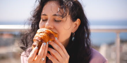 vrouw hapt in croissant met ogen dicht